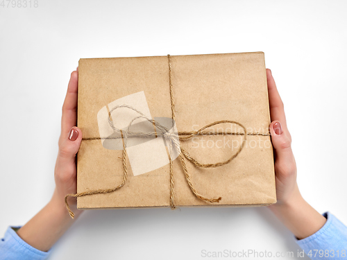 Image of hands with parcel box tied by rope at post office