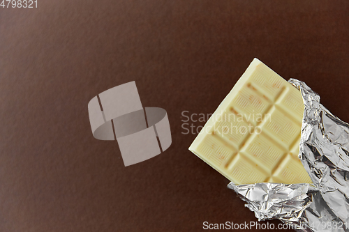 Image of white chocolate bar in foil wrapper on brown