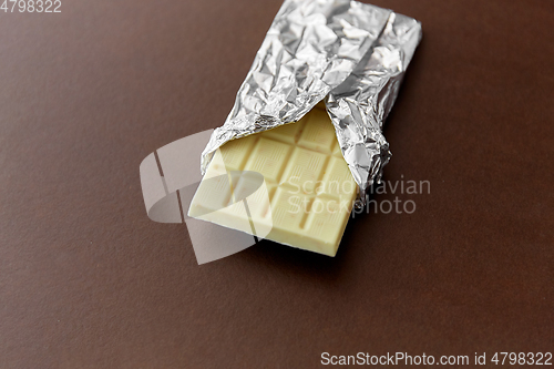 Image of white chocolate bar in foil wrapper on brown