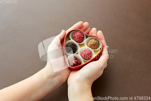 Image of hands with candies in heart shaped chocolate box