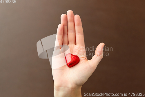 Image of hand with red heart shaped chocolate candy