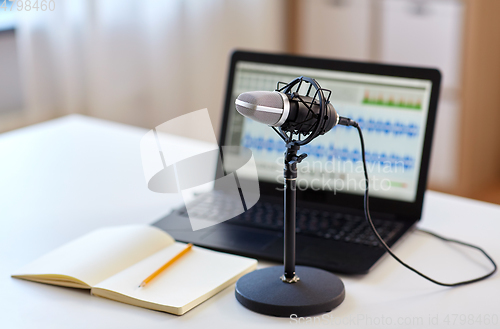 Image of microphone, laptop and notebook on table