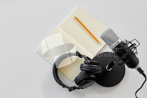 Image of headphones, microphone and notebook with pencil