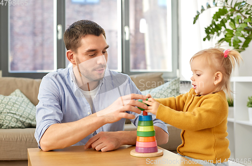 Image of father playing with little baby daughter at home