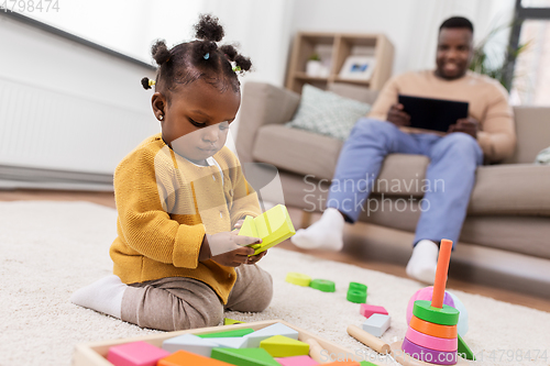 Image of african baby girl playing with toy blocks at home