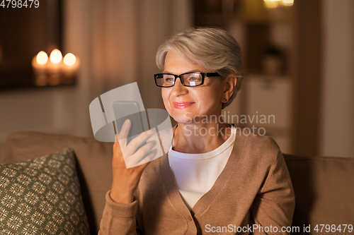 Image of happy senior woman with smartphone at home