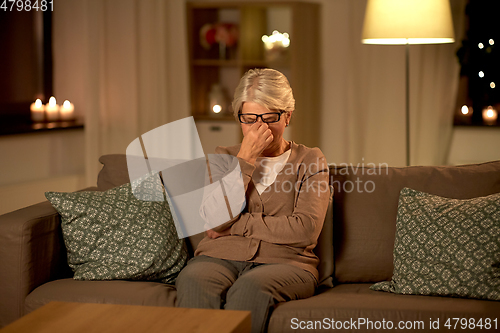 Image of tired senior woman in glasses at home at night
