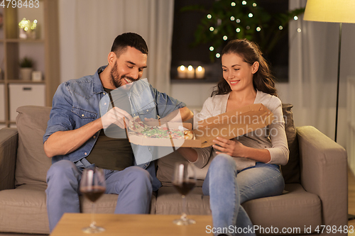 Image of happy couple eating takeaway pizza at home