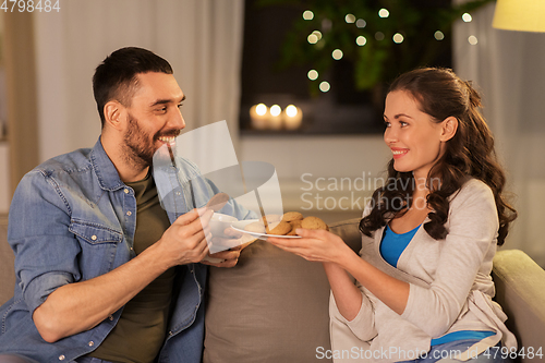 Image of happy couple drinking tea with cookies at home