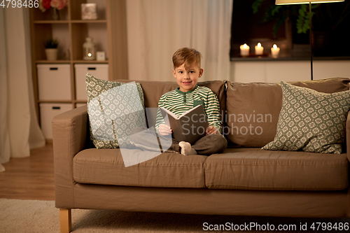 Image of happy little boy reading book at home