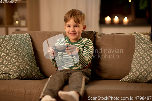 Image of little boy with gamepad playing video game at home