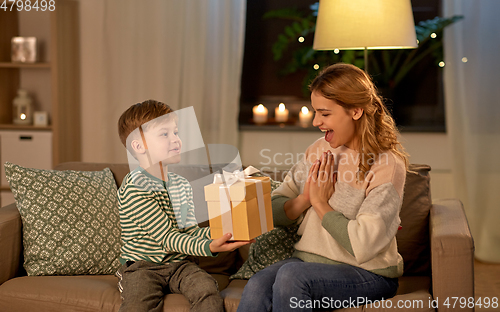 Image of little son giving present to mother at home