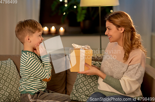 Image of mother giving present to her little son at home