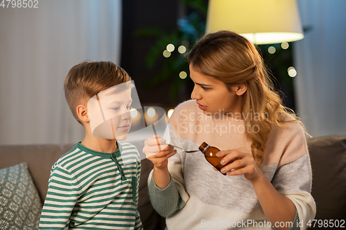 Image of mother giving medication or cough syrup to ill son