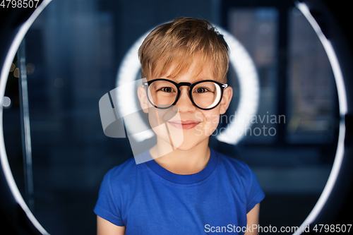 Image of boy in glasses over illumination in dark room