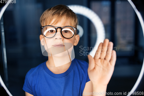 Image of boy in glasses over illumination in dark room