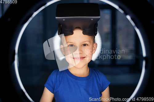 Image of boy in vr glasses over illumination in dark room