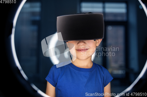 Image of boy in vr glasses over illumination in dark room