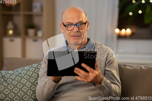 Image of happy senior man with tablet computer at home