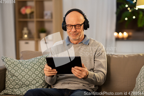 Image of senior man with tablet pc and headphones at home