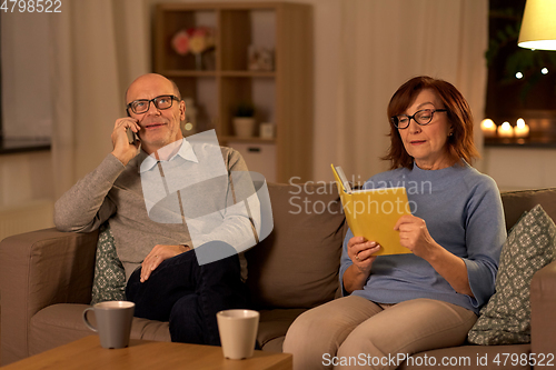 Image of senior couple with book and smartphone at home