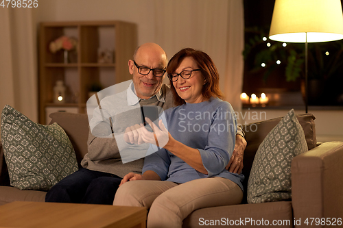 Image of happy senior couple with smartphone at home