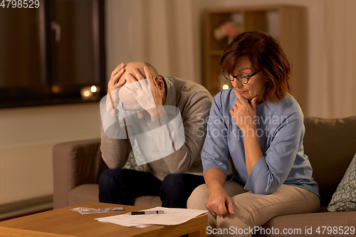 Image of unhappy senior couple with bills and money at home