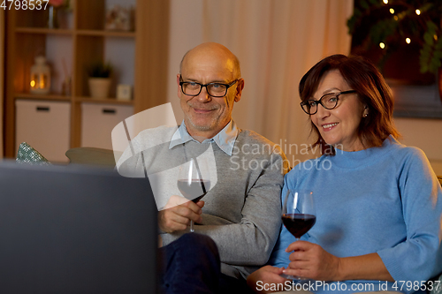 Image of happy senior couple drink red wine and watch tv