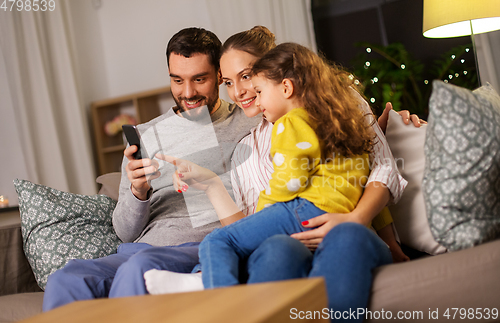 Image of happy family with smartphone at home at night