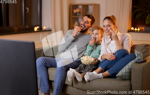 Image of happy family with popcorn watching tv at home