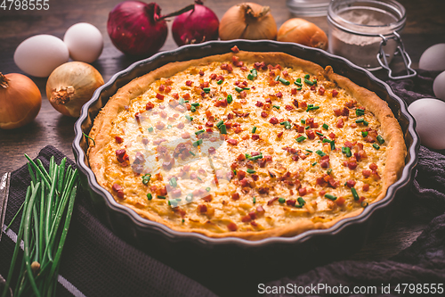 Image of Homemade onion tart or pie with bacon and chives