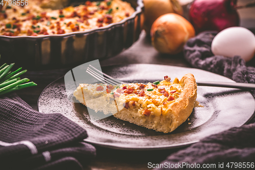 Image of Piece of homemade onion tart or pie with bacon and chives