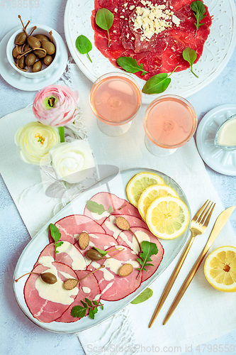 Image of Appetizers - Vitello tonnato and beef Carpaccio with two glasses of rose wine