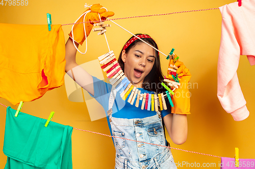 Image of Funny and beautiful housewife doing housework on yellow background