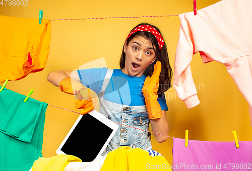 Image of Funny and beautiful housewife doing housework on yellow background