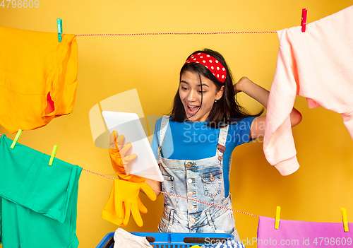 Image of Funny and beautiful housewife doing housework on yellow background