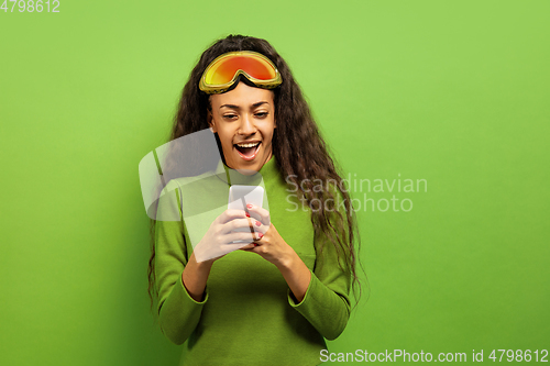 Image of African-american young woman\'s portrait in ski mask on green background