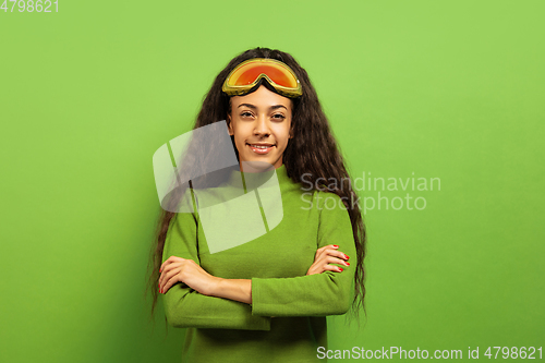 Image of African-american young woman\'s portrait in ski mask on green background
