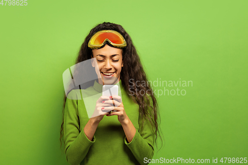 Image of African-american young woman\'s portrait in ski mask on green background