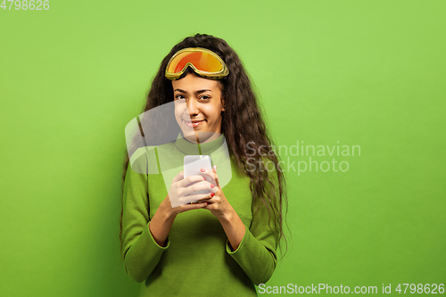 Image of African-american young woman\'s portrait in ski mask on green background