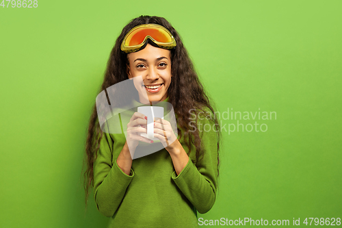 Image of African-american young woman\'s portrait in ski mask on green background