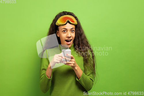 Image of African-american young woman\'s portrait in ski mask on green background