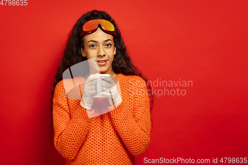 Image of African-american young woman\'s portrait in ski mask on red background