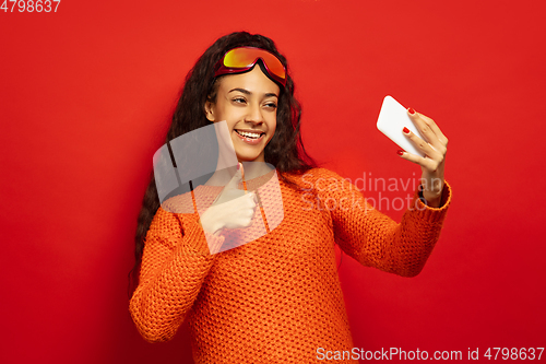 Image of African-american young woman\'s portrait in ski mask on red background