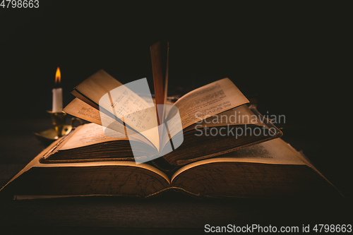 Image of Old antique books with candle in vintage style on black background