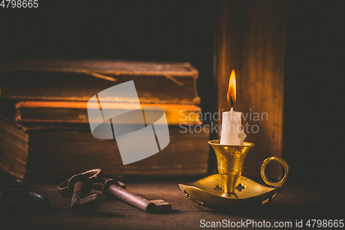 Image of Pile of old antique books with candle in vintage style on black background