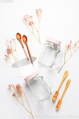 Image of Empty drinking cups or jars with wooden spoons on white background