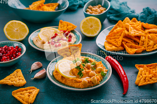 Image of Homemade spicy humus with pomegranate seeds, chilli and chickpeas tortilla chips