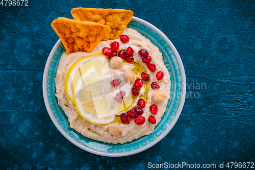 Image of Homemade spicy humus with pomegranate seeds and chickpeas tortilla chips