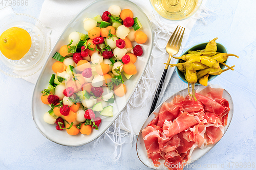 Image of Cucumber and melon salad with raspberries and Prosciutto with grilled peppers 